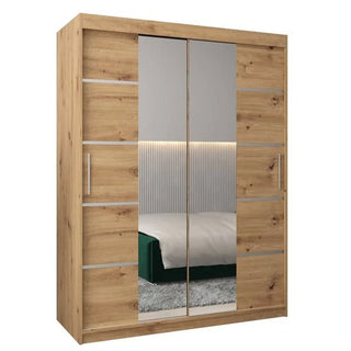 The Vevey III Mirrored Wardrobe features two sliding doors with central mirrors and horizontal metal accents in Artisan Oak. The reflected image shows part of a bed and a vertically lined wall.