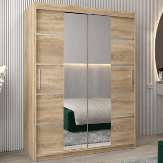 The Vevey III Mirrored Wardrobe with 2 sliding doors in Sonoma Oak (150cm) stands in a modern bedroom with a striped wall, reflecting a bed with a green base and showing part of a round mirror and vase.