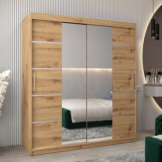 The Vevey III Mirrored Wardrobe with 2 sliding doors in artisan oak (180cm) stands in a modern bedroom, featuring silver horizontal accents and reflecting the bed, rug, and wall decor.