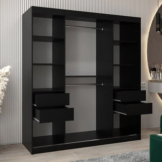 The Vevey III Mirrored Wardrobe with 2 sliding doors in black (180cm) features two hanging rods, multiple shelves, and four drawers—some open—against a light vertical-lined wall, accented by a green chair and decorative items.
