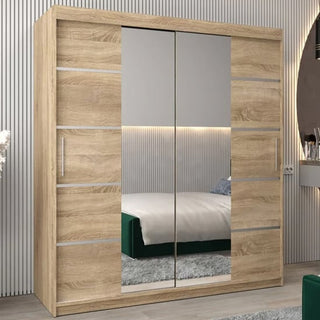 The Vevey III Mirrored Wardrobe 2 Sliding Doors 180cm in Sonoma Oak stands by a wall with vertical grooves, reflecting a bed with a green blanket and a modern minimalist bedroom interior.