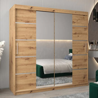 The Vevey III Mirrored Wardrobe 2 Sliding Doors 200cm in Artisan Oak adds modern style with mirrored sliding doors and vertical metallic handles. Reflections show a bed with a green headboard and part of a rug.