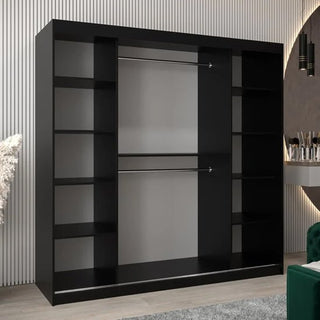 The Vevey III Mirrored Wardrobe with 2 black sliding doors (200cm) has central metal hanging rods and side shelves, set against a wall with vertical lines. A green chair and vanity appear on the right.
