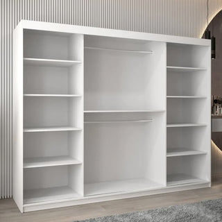 The Vevey III Mirrored Wardrobe with 3 sliding doors (250cm, white) features open shelving on both sides and two hanging rods in the center. It stands on a wooden floor against a vertically lined wall, with a soft rug partially visible below.