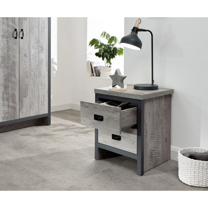 Grey two-drawer bedside table with black handles, desk lamp and star decoration