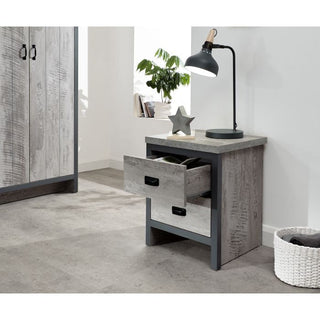 Grey two-drawer bedside table with black handles, desk lamp and star decoration