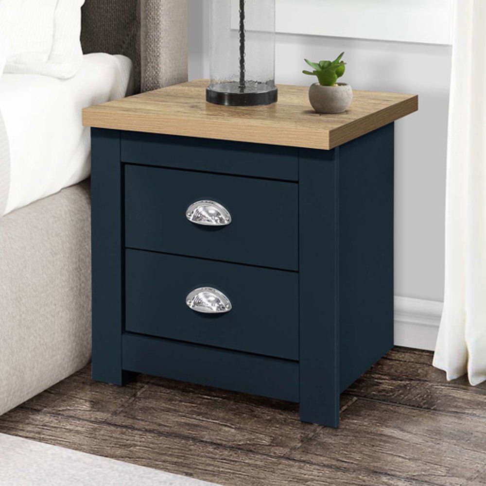 Highland navy blue and oak 2-drawer bedside cabinet with silver handles, shown next to a bed.