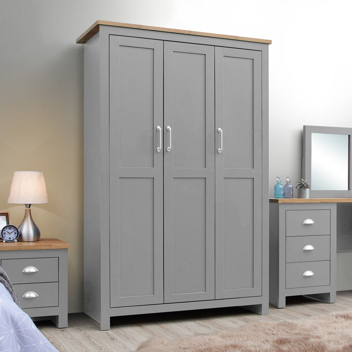 Light grey 3 door wardrobe with oak effect top, beside matching nightstand and dresser.