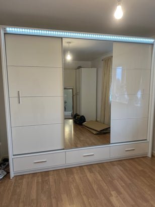 White high gloss 255cm sliding wardrobe with 3 drawers and LED lighting.