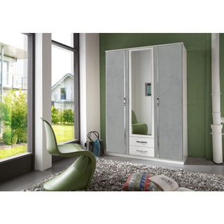 A modern room features a green chair, the DAYTON 3 Door Wardrobe in white and grey (135cm) with mirrored doors and drawers, a bag on the floor, a shaggy gray rug, and large windows overlooking houses and greenery.