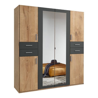 The FENTON 4 Door 4 Drawers Mirrored Wardrobe in Oak and Graphite (180cm) features wood grain panels, two mirrored doors, and dark gray accents. The mirrors reflect a bed with a gold blanket.