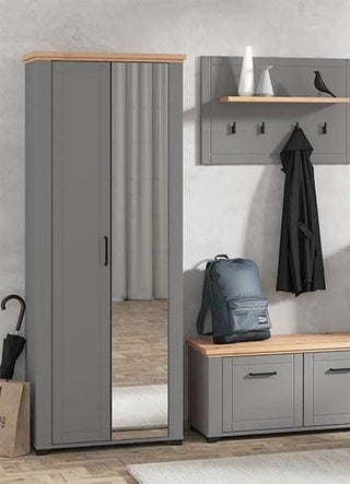 A modern entryway with the HESTA 2 Door Mirrored Wardrobe in Grey and Artisan Oak (75cm), a storage bench, a coat rack with hooks, a backpack, and decor items displayed on a wall shelf.
